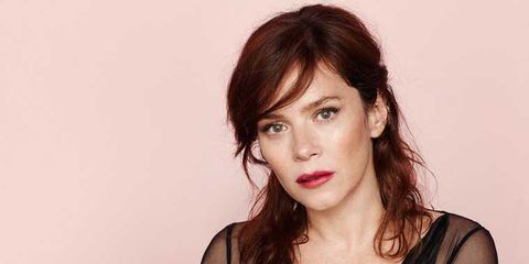 actress anna friel with her brunette hair pulled partially up and a serious look on her face wearing a black mesh shirt